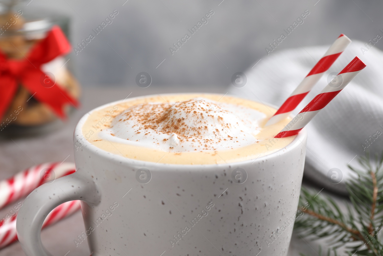 Photo of Cup of delicious eggnog with cinnamon on table, closeup