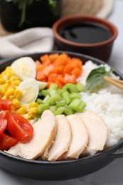 Photo of Delicious poke bowl with meat, egg, rice and vegetables on table, closeup