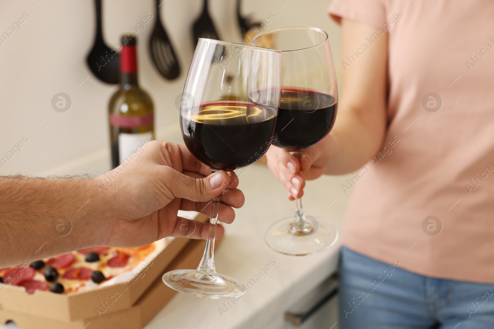 Photo of Couple clinking glasses of wine at home, closeup