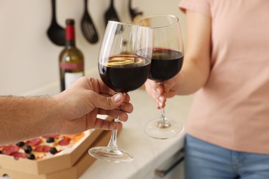 Couple clinking glasses of wine at home, closeup
