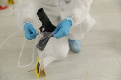 Photo of Investigator in protective suit working at crime scene indoors, closeup
