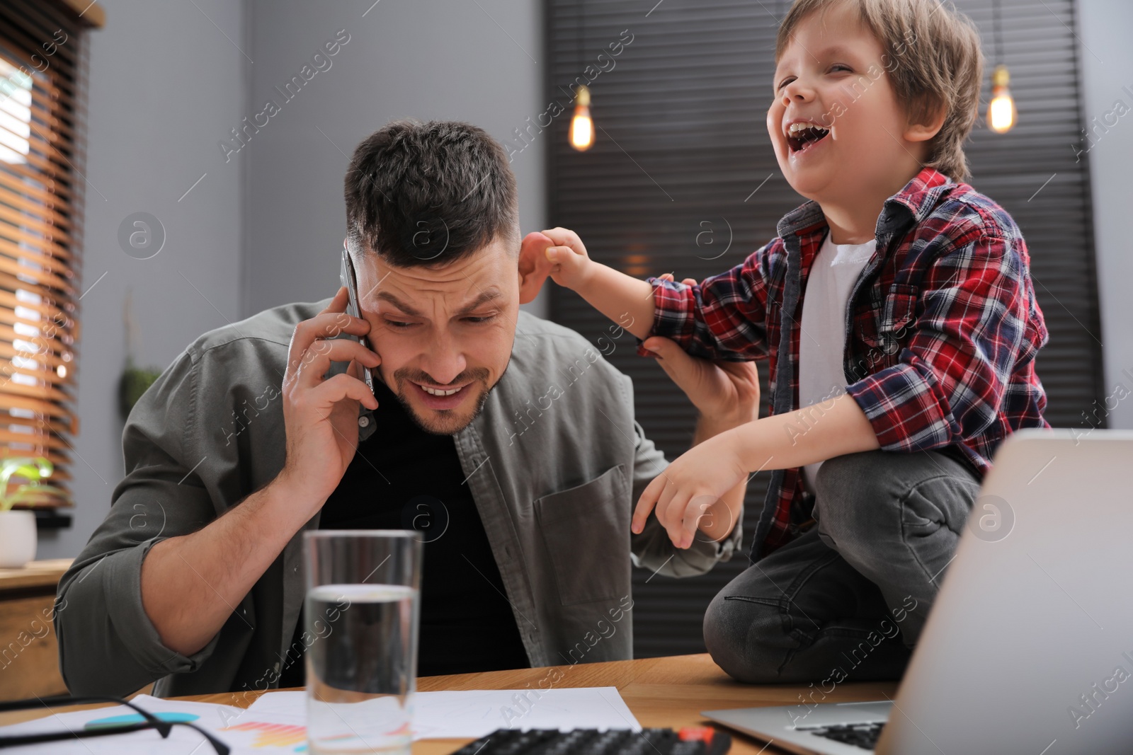 Photo of Overwhelmed man combining parenting and work at home