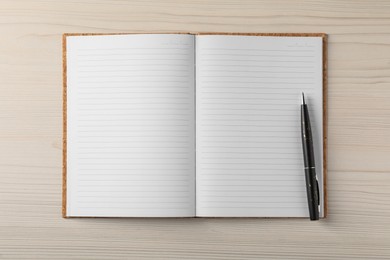 Photo of Empty notebook and pen on wooden table, top view