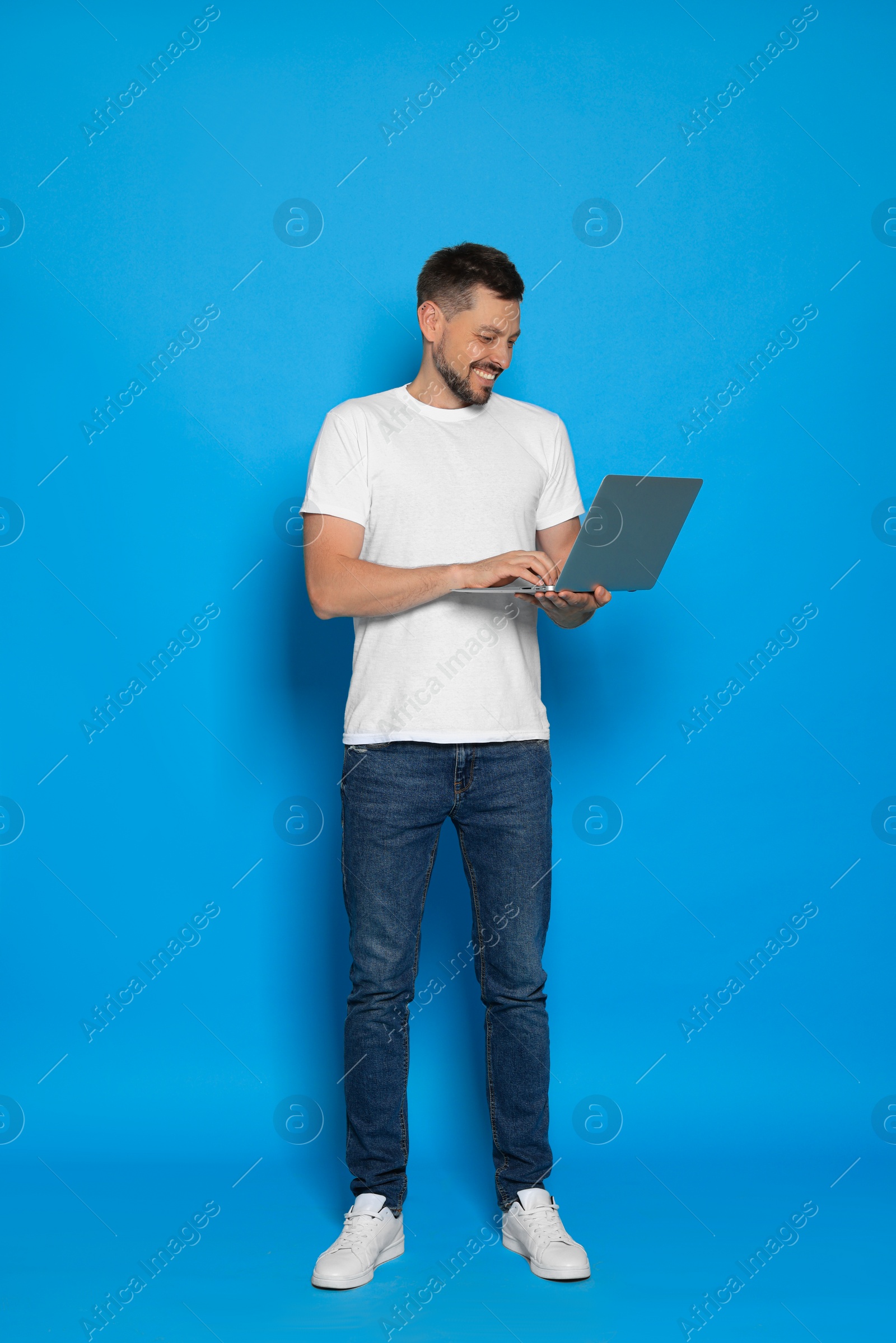 Photo of Happy man looking at laptop on light blue background