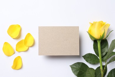 Photo of Beautiful yellow rose, petals and blank card on white background, flat lay. Space for text