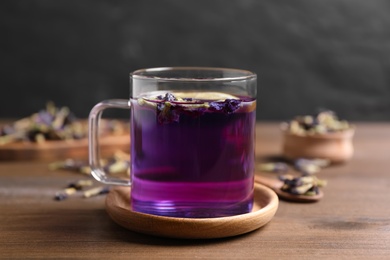 Photo of Glass mug of organic blue Anchan on wooden table. Herbal tea