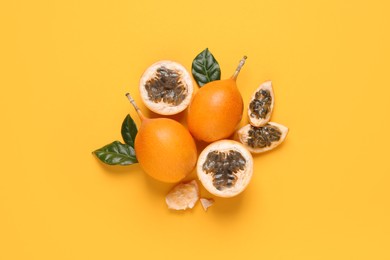 Photo of Delicious ripe granadillas with leaves on yellow background, flat lay