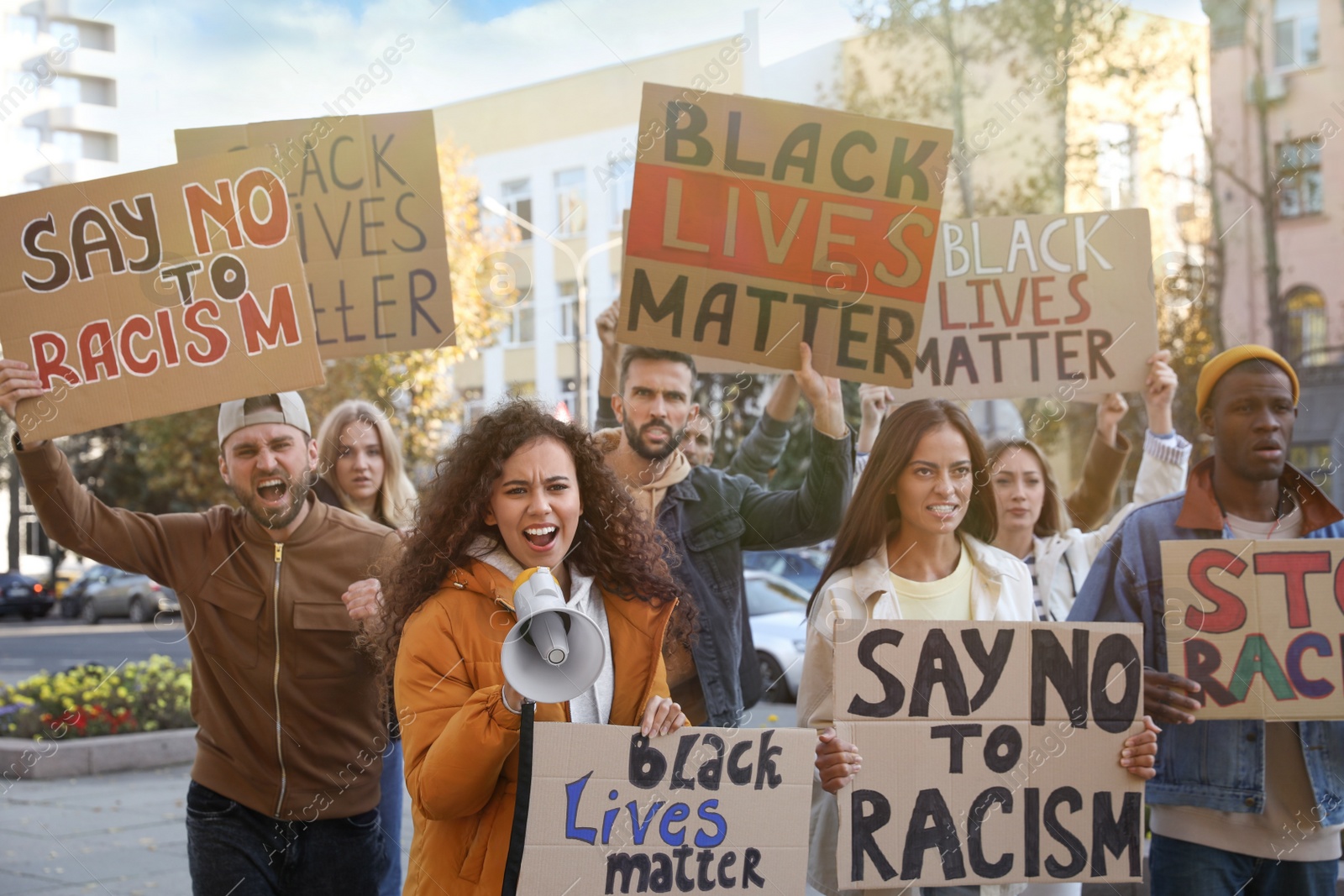 Photo of Protesters demonstrating different anti racism slogans outdoors. People holding signs with phrases