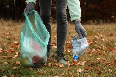 Photo of Woman with trash bag collecting garbage in nature, closeup