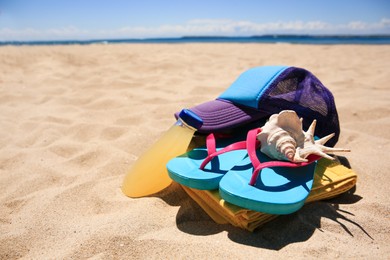 Photo of Cap, flip flops, seashell and refreshing drink on beach, space for text
