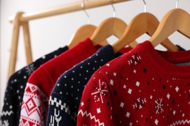 Photo of Rack with different Christmas sweaters on light background, closeup