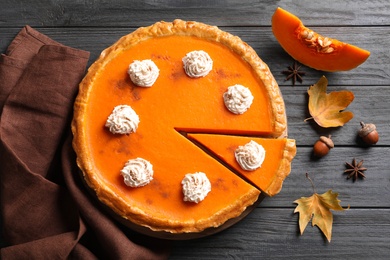 Fresh delicious homemade pumpkin pie with whipped cream on wooden background, flat lay