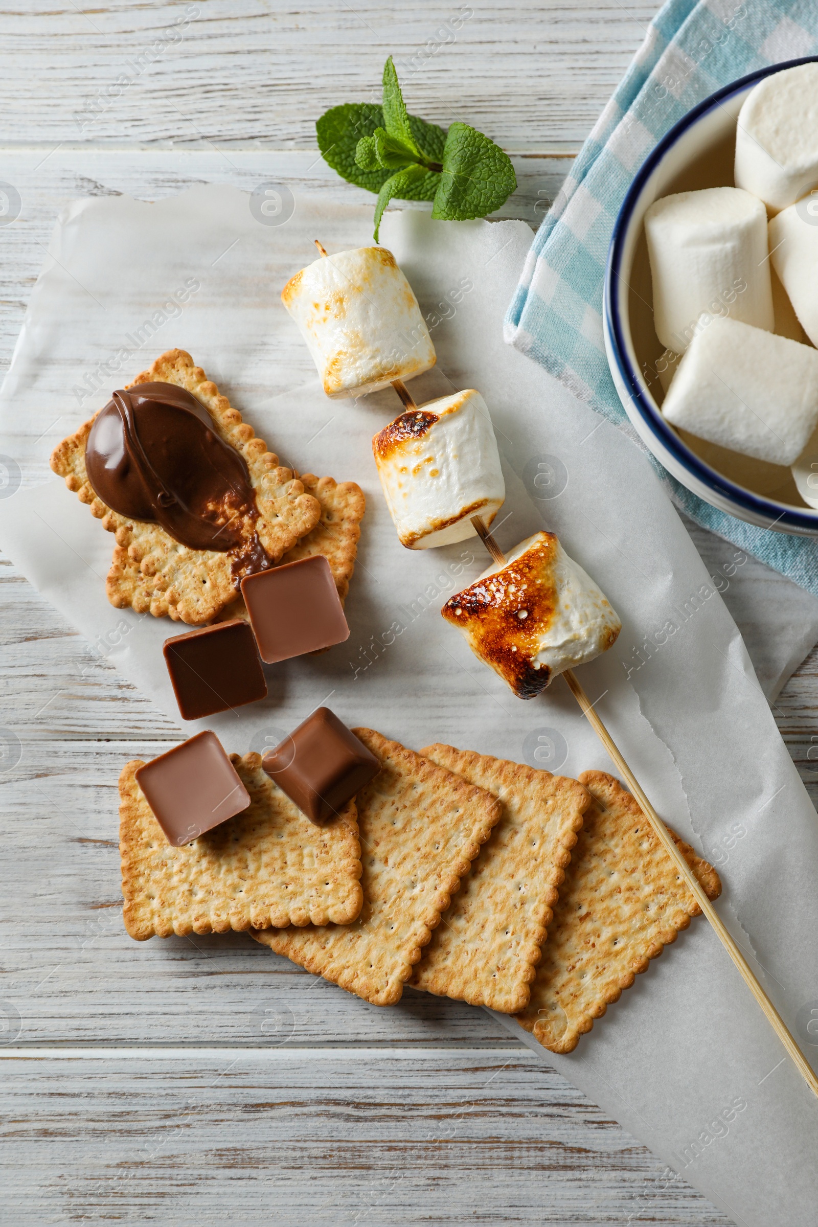 Photo of Ingredients for delicious sandwich with roasted marshmallows and chocolate on white wooden table, flat lay