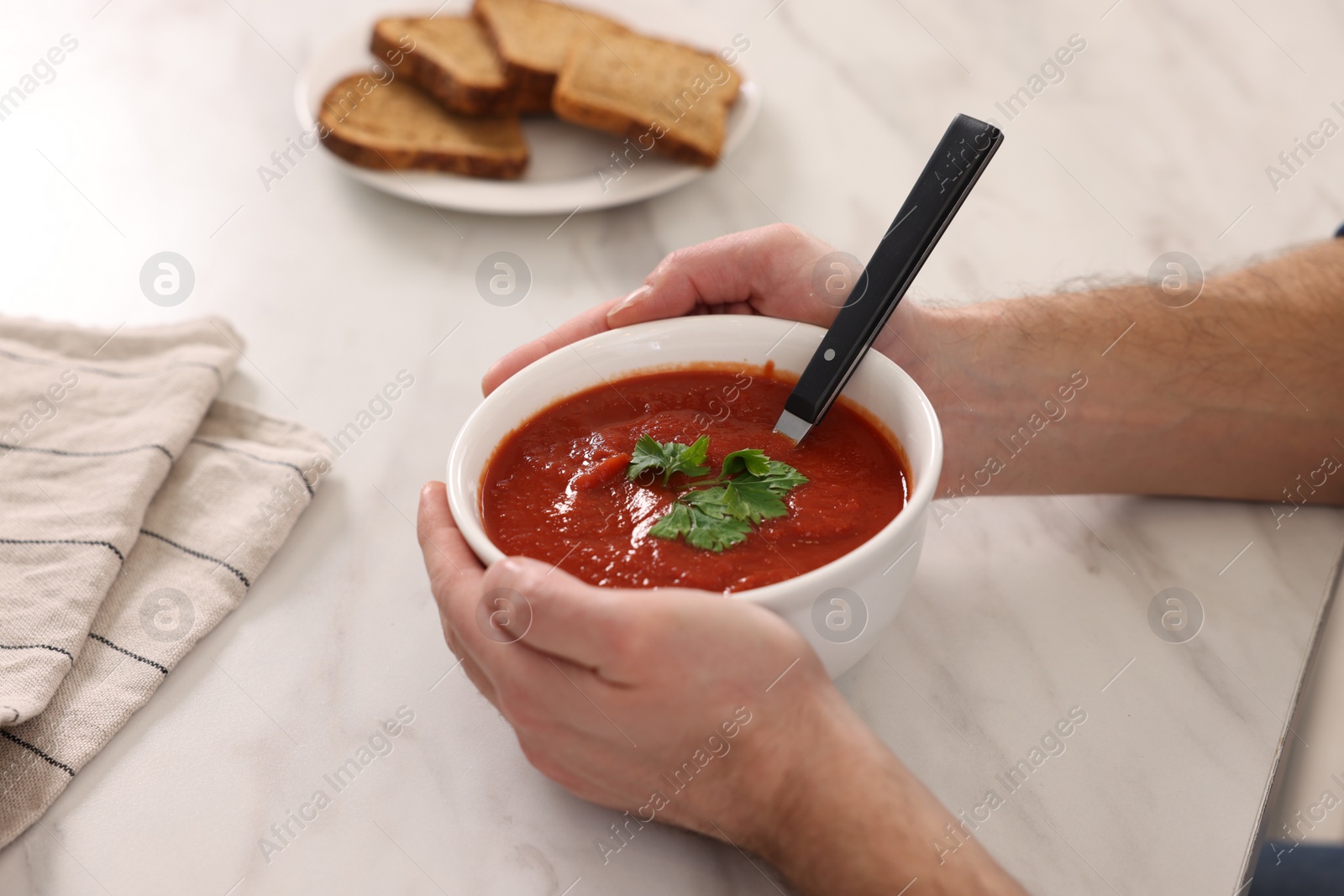 Photo of Man with delicious tomato soup at light marble table, closeup