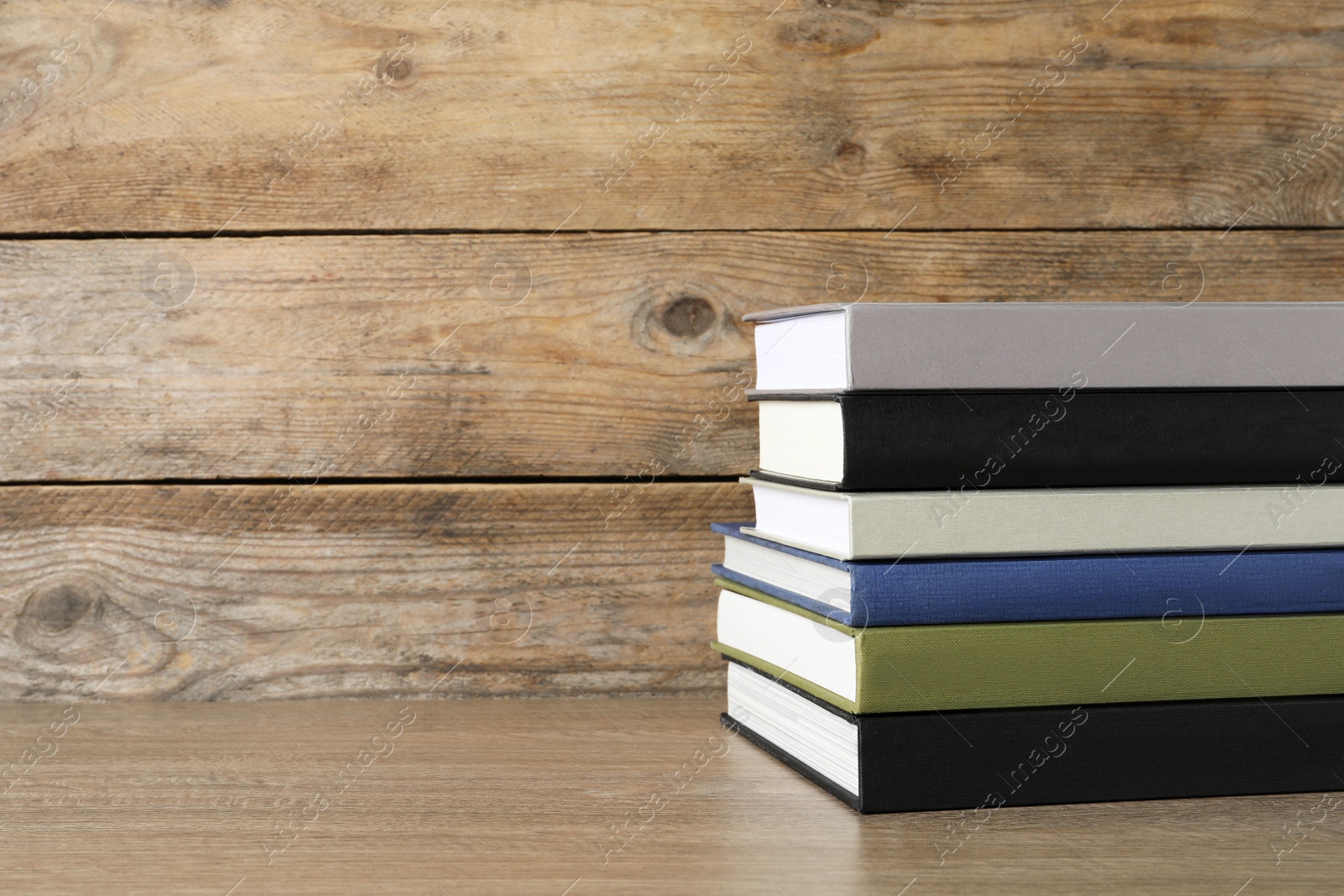 Photo of Stack of hardcover books on wooden table, space for text