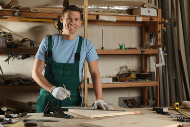 Photo of Professional carpenter measuring wooden board in workshop