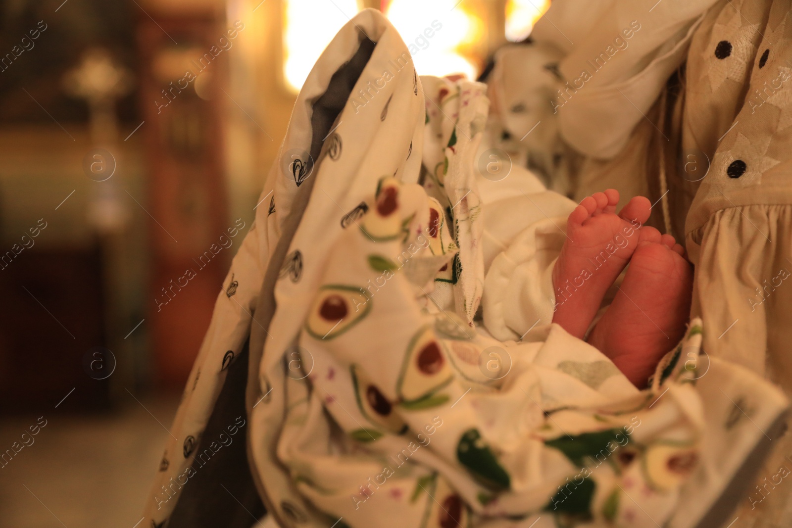 Photo of Stryi, Ukraine - September 11, 2022: Mother holding child during baptism ceremony in Assumption of Blessed Virgin Mary cathedral, closeup