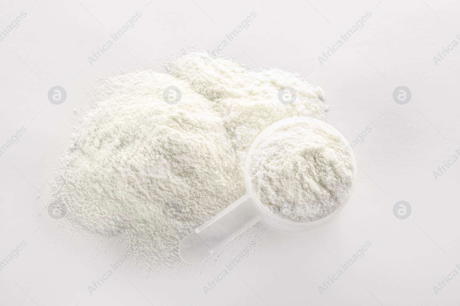 Photo of Scoop and pile of protein powder on white background, top view