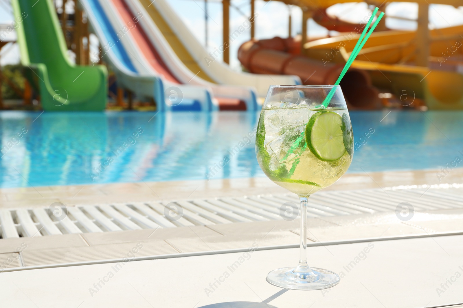 Photo of Glass of delicious mojito near swimming pool, space for text. Refreshing drink