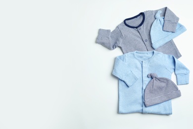 Photo of Flat lay composition with caps, bodysuits and space for text on white background. Baby accessories