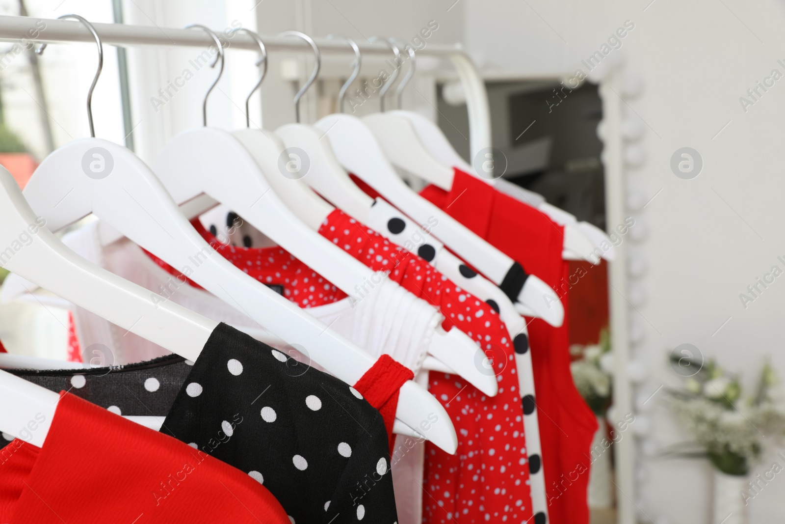 Photo of Rack with stylish hanging clothes in dressing room