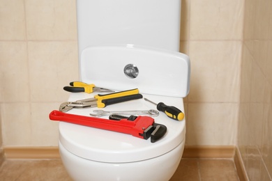 Different plumber's tools on toilet seat lid indoors