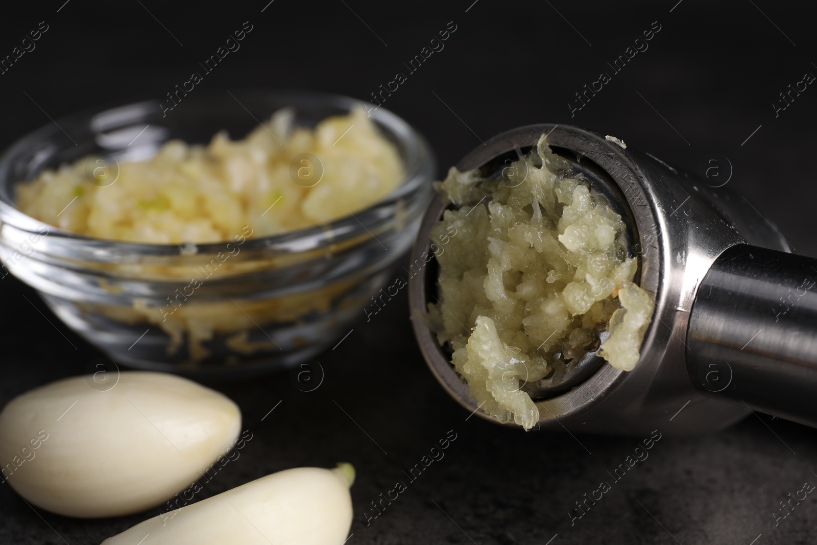 Photo of Garlic press, cloves and mince on grey table, closeup