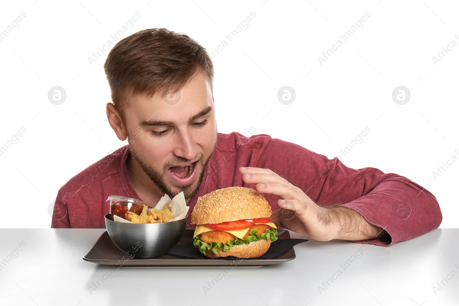 Photo of Young man and plate with French fries and tasty burger on white background