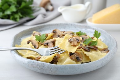 Photo of Delicious ravioli with mushrooms and fork on white table, closeup