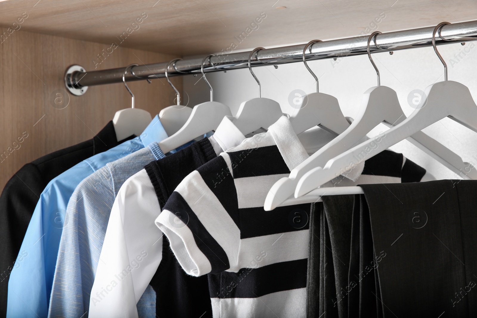 Photo of Stylish boy's clothes hanging in wardrobe, closeup