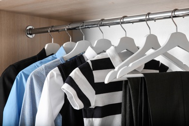 Photo of Stylish boy's clothes hanging in wardrobe, closeup