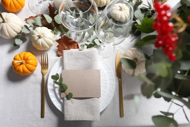 Photo of Beautiful autumn table setting. Plates, cutlery, glasses, blank card and floral decor, flat lay