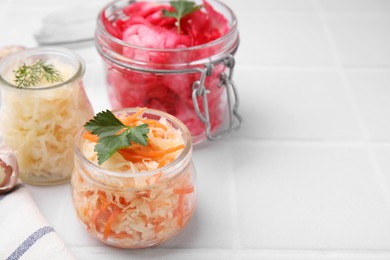 Photo of Delicious sauerkraut prepared according to different recipes on white table, closeup. Space for text