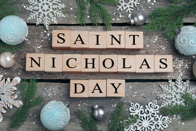 Photo of Cubes with phrase Saint Nicholas Day and festive decor on wooden table, flat lay