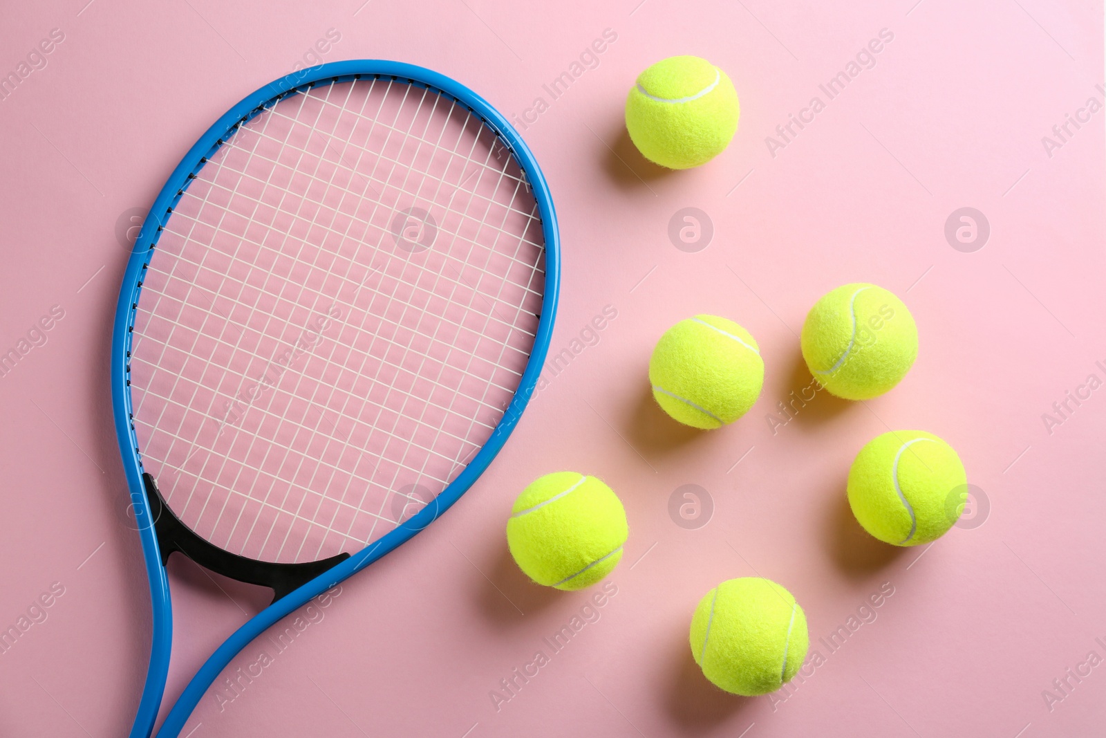 Photo of Tennis racket and balls on pink background, flat lay. Sports equipment