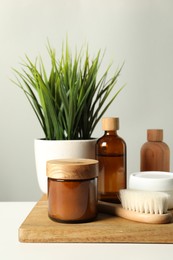 Different bath accessories and houseplant on white table against grey background