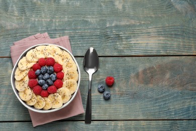 Photo of Tasty breakfast dish with berries, banana and chia seeds served on wooden table, flat lay. Space for text