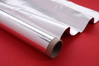 Photo of One roll of aluminum foil on red background, closeup