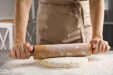 Woman rolling fresh dough at table, closeup