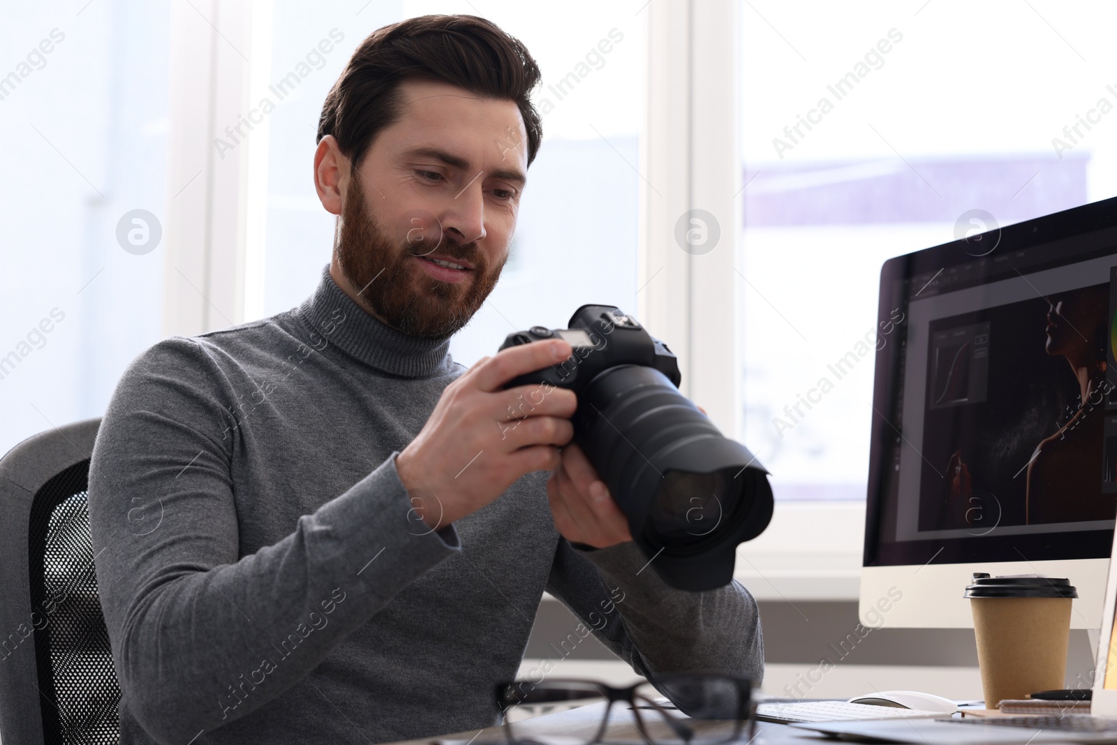 Photo of Professional photographer with digital camera at table indoors