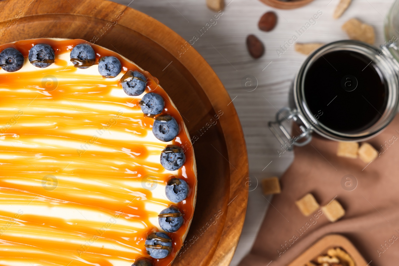 Photo of Delicious cheesecake with caramel and blueberries on white wooden table, top view. Space for text