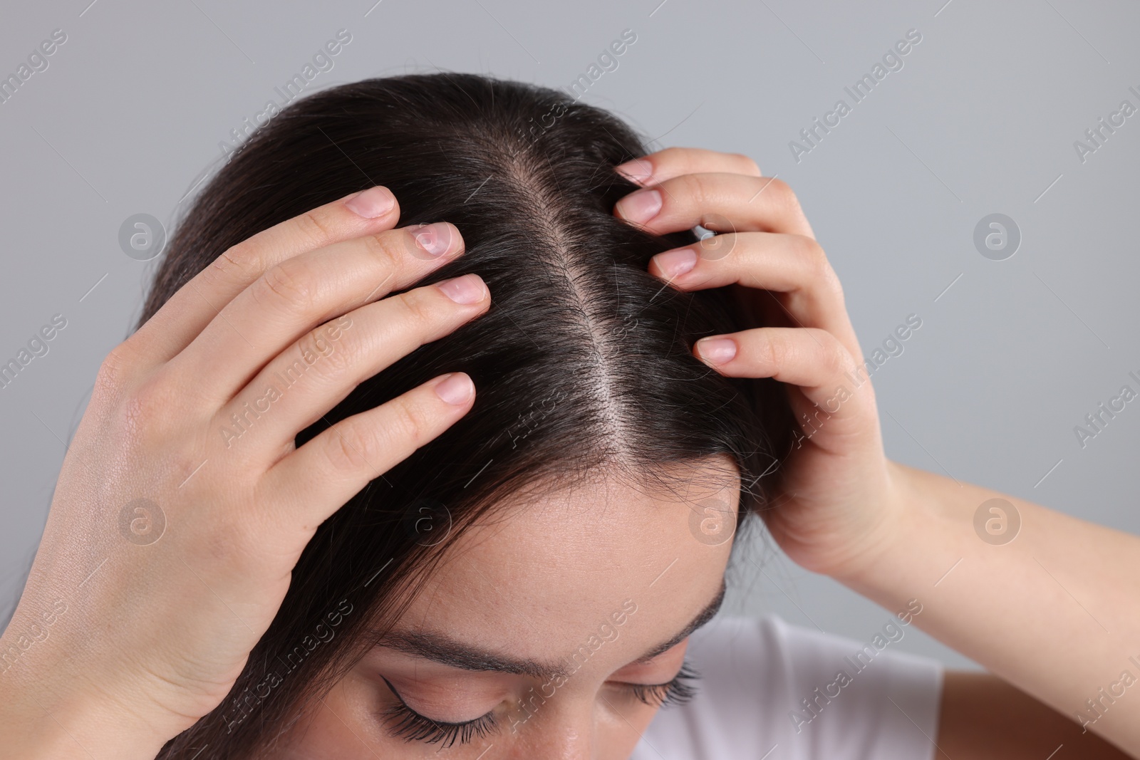 Photo of Woman examining her hair and scalp on grey background, closeup