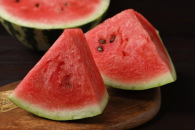 Photo of Slices of tasty ripe watermelon on dark wooden table, closeup