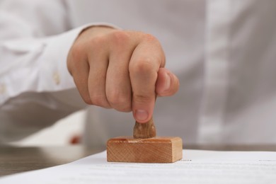 Photo of Man stamping document at table, closeup view