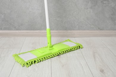 Cleaning dirty wooden floor with mop indoors