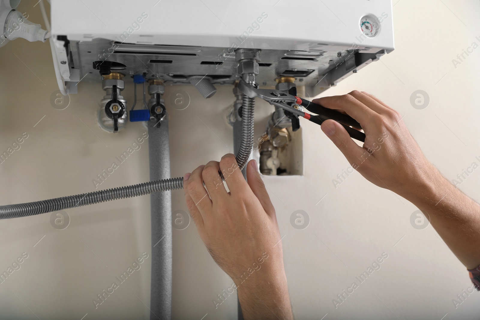 Photo of Man repairing gas boiler with waterpump plier, closeup
