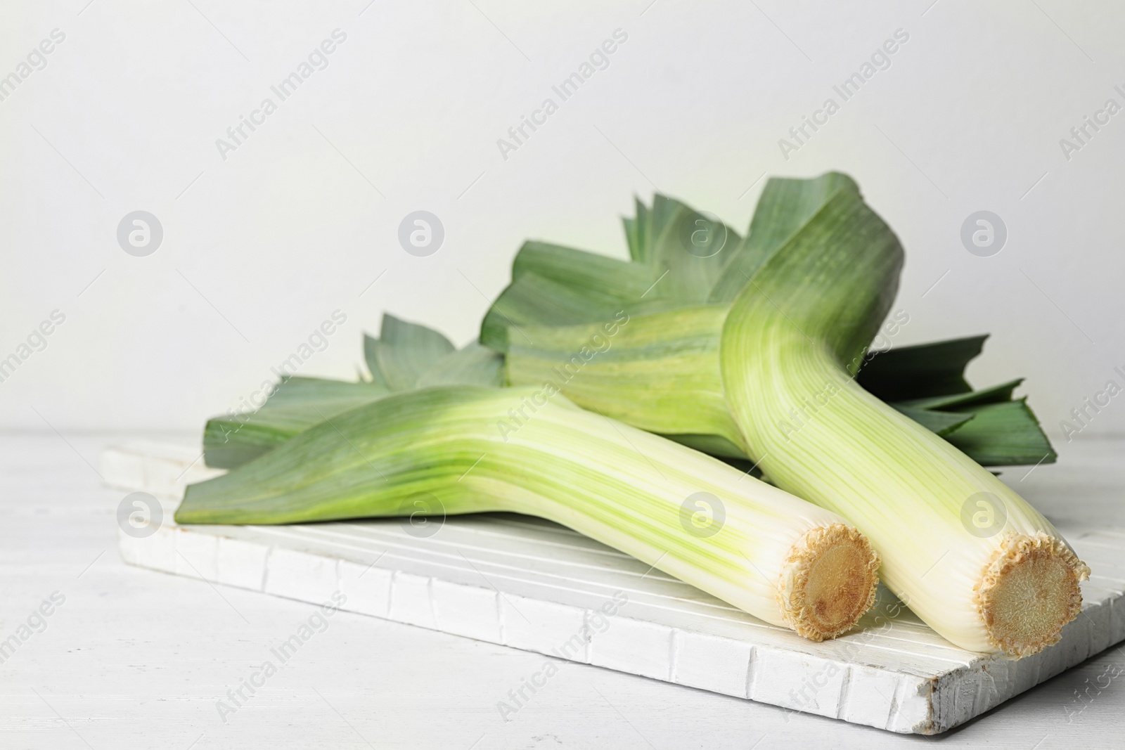 Photo of Fresh raw leeks on white wooden table. Ripe onion