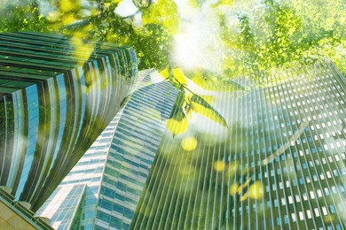 Image of Go green concept. Low angle view of modern building and trees on sunny day
