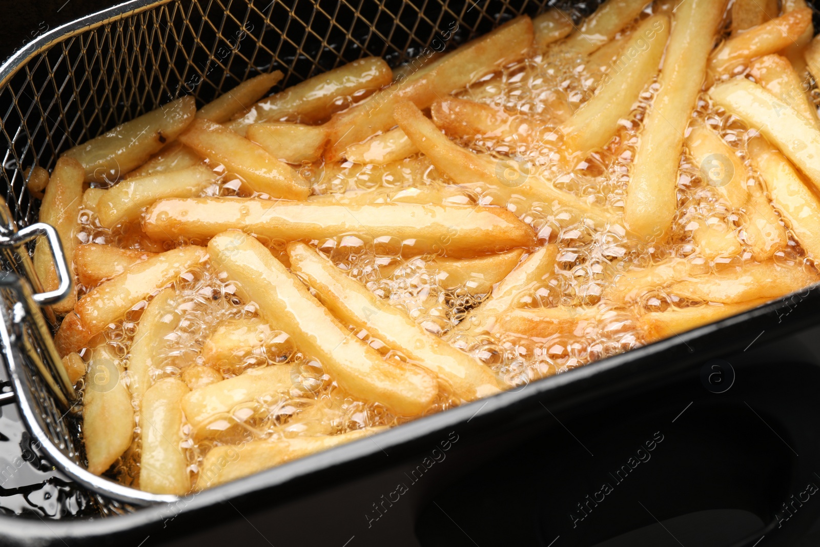 Photo of Cooking delicious french fries in hot oil, closeup