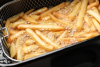 Photo of Cooking delicious french fries in hot oil, closeup